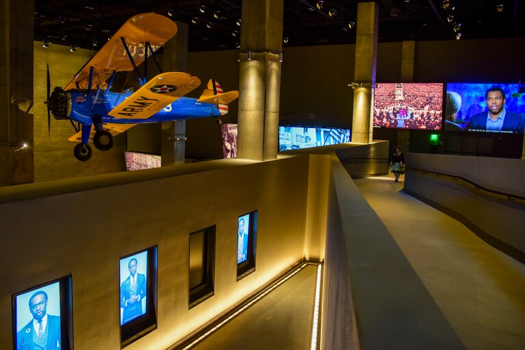 Walkways lead visitors past multimedia presentations and a Tuskegee institute training aircraft in the “Defending Freedom, Defining Freedom” exhibition at the National Museum of African American History and Culture. (Jahi Chikwendiu/The Washington Post)